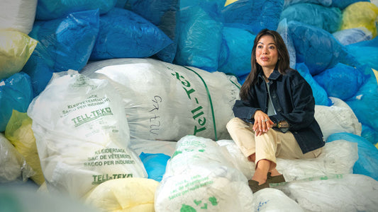Annabelle is sitting in a pile of bags of used textiles