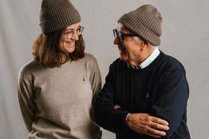 Eine Frau und ein Mann schauen sich lachend an und tragen Strickkleider.